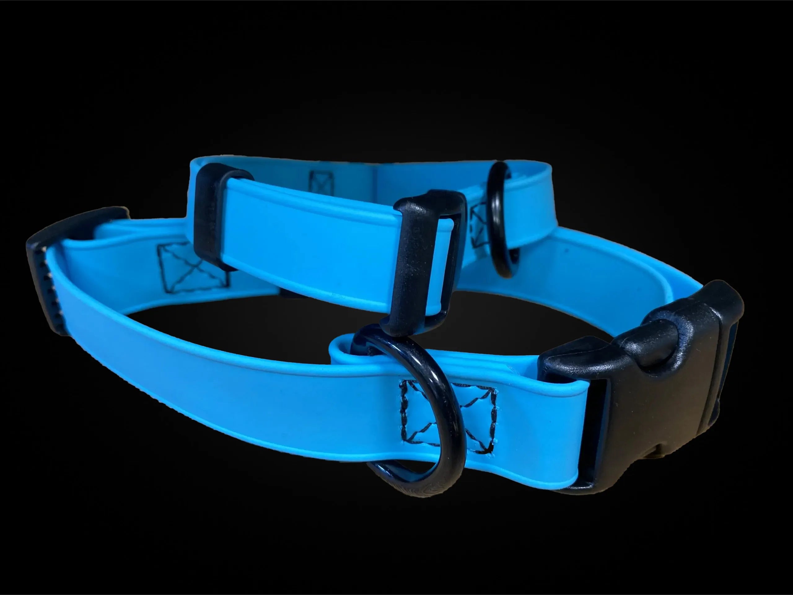 Blaues Biothane Hundehalsband mit schwarzer Kunststoffschnalle und Metall-D-Ringen auf dunklem Hintergrund