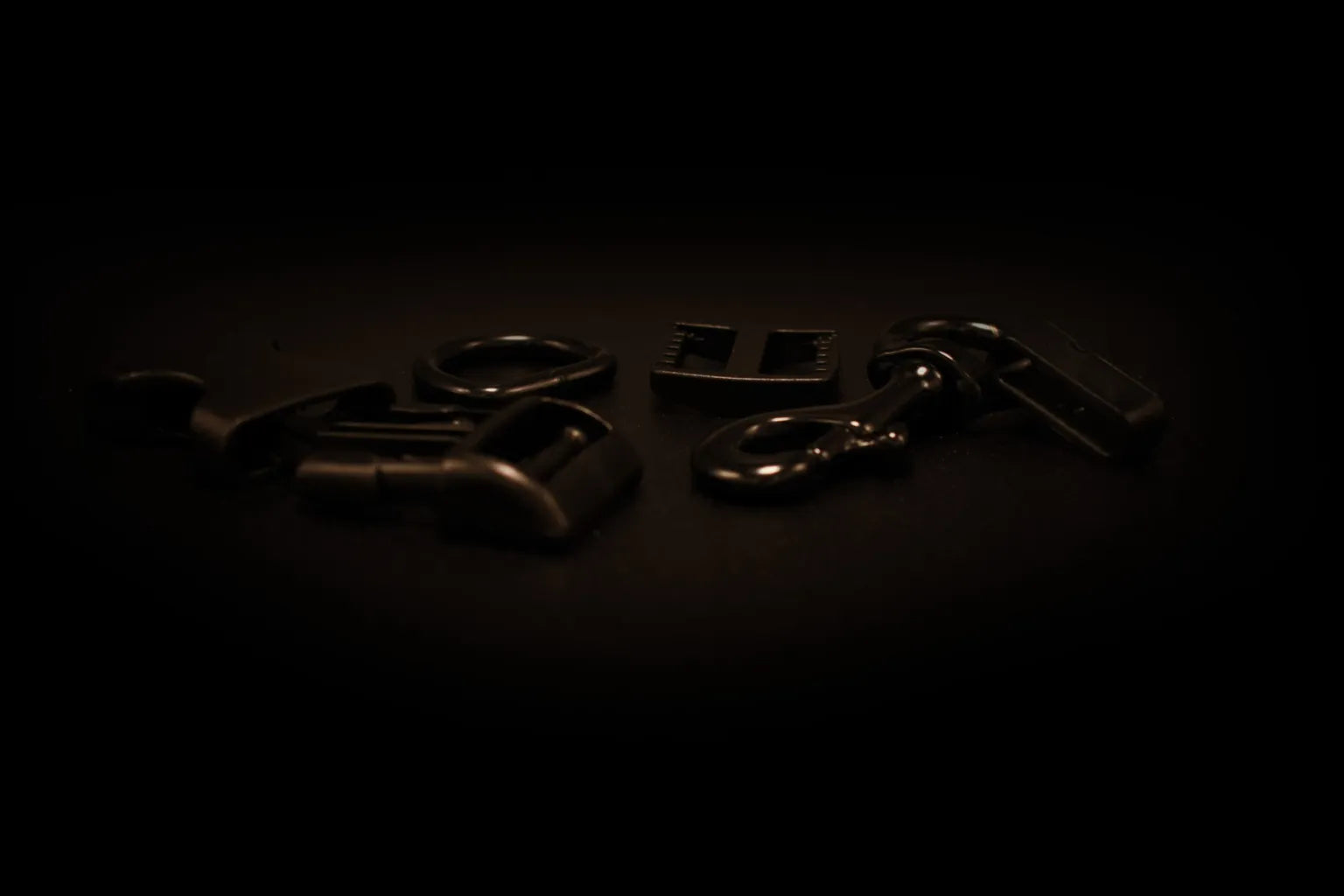 Set aus schwarzen Metallschnallen, Karabinern und Beschlägen auf dunkler Oberfläche