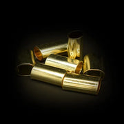 Mehrere zylindrische Metallhülsen mit glänzender goldfarbener Oberfläche auf einer dunklen Fläche angeordnet