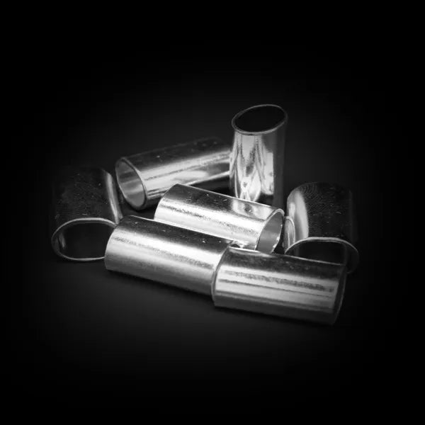 Mehrere zylindrische Metallhülsen mit glatter silberfarbener Oberfläche zusammen auf einer dunklen Fläche angeordnet